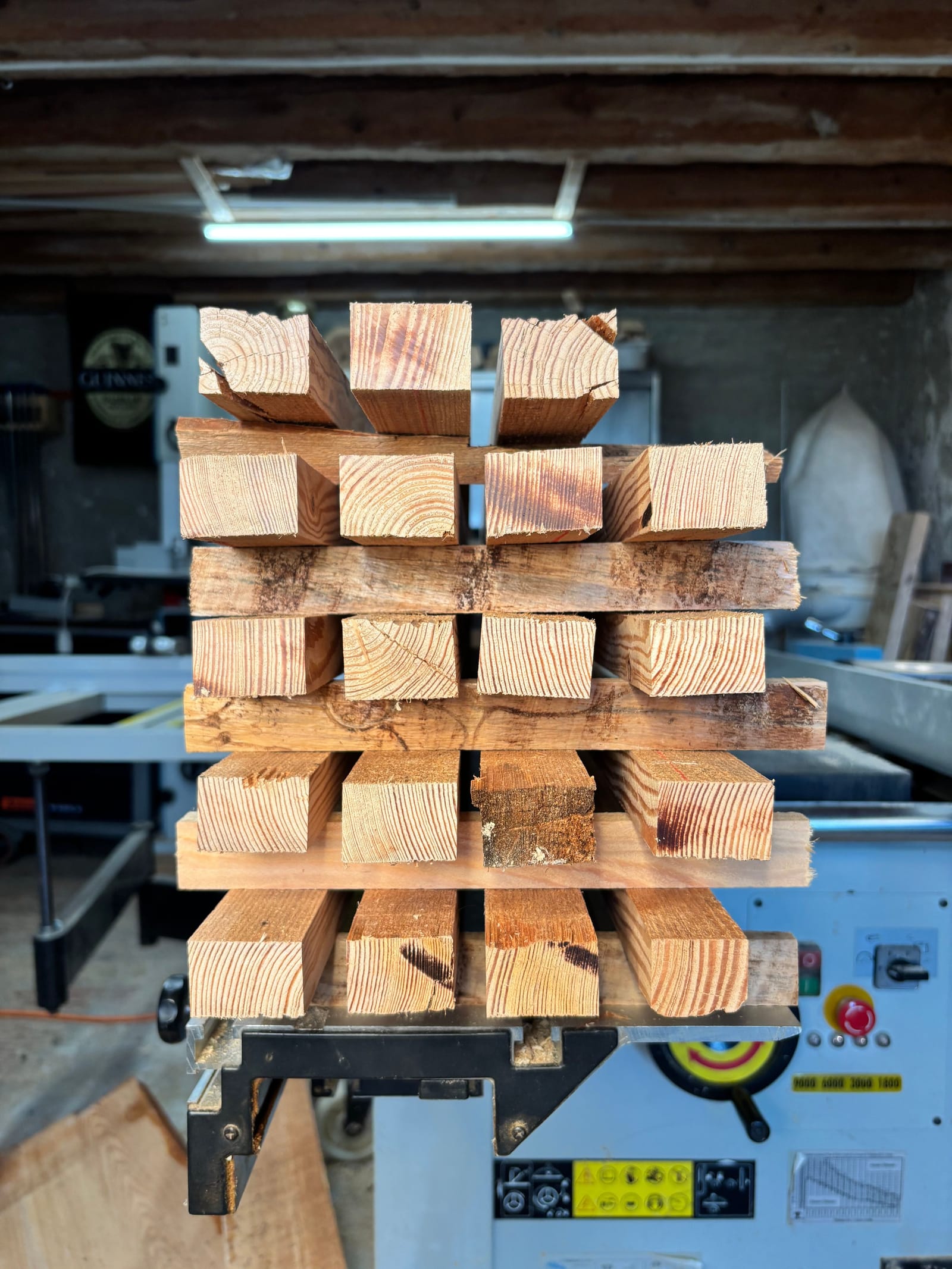 Sections de bois empilées et croisées sur la table de sciage de l'atelier, vues en bout.